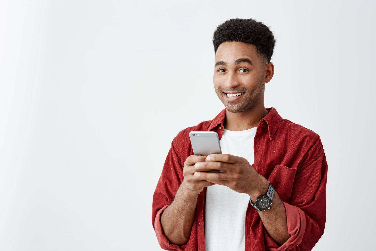 positive-emotions-close-up-young-good-looking-dark-skinned-male-with-afro-hairstyle-white-t-shirt-red-shirt-smiling-with-teeth-chatting-with-friend-smartphone